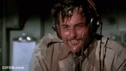 A Man Wearing Headphones Is Sweating And Smiling While Sitting On An Airplane . GIF