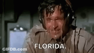 A Man Wearing Headphones Is Sweating While Sitting On A Plane And Saying `` Florida '' . GIF
