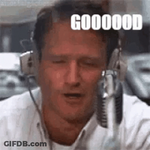 A Man Wearing Headphones Is Talking Into A Microphone And Making A Funny Face . GIF
