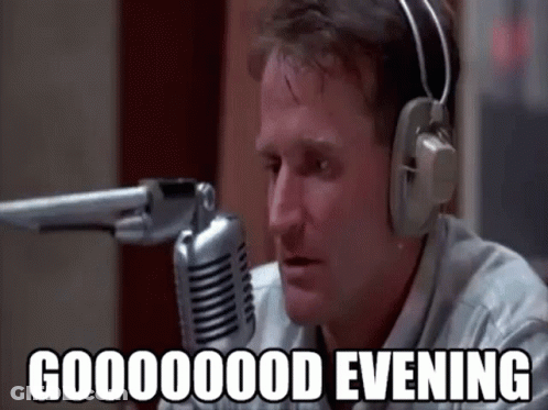 A Man Wearing Headphones Is Talking Into A Microphone And Saying `` Good Evening '' . GIF