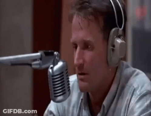 A Man Wearing Headphones Is Talking Into A Microphone In A Studio . GIF