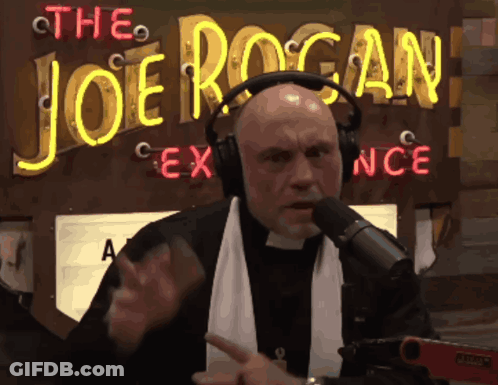 A Man Wearing Headphones Is Talking Into A Microphone In Front Of A Neon Sign That Says The Joe Rogan GIF