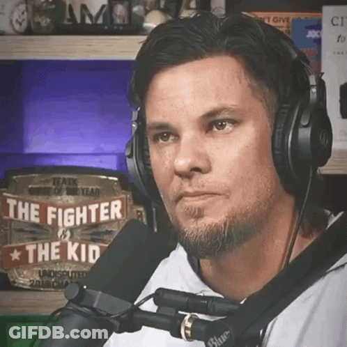 A Man Wearing Headphones Is Talking Into A Microphone With A Sign That Says The Fighter And The Kid GIF