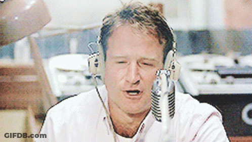 A Man Wearing Headphones Is Talking Into A Microphone With His Eyes Closed GIF
