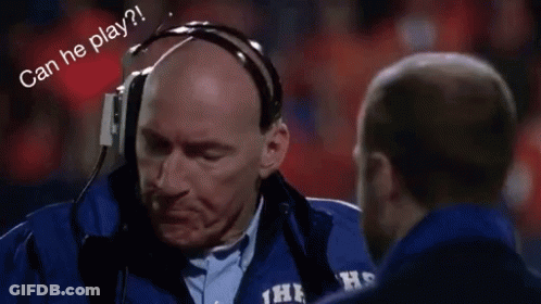 A Man Wearing Headphones Is Talking To Another Man On A Field . GIF