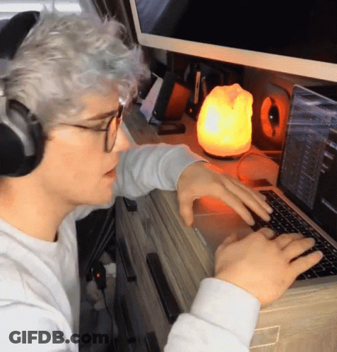 A Man Wearing Headphones Is Typing On His Laptop GIF