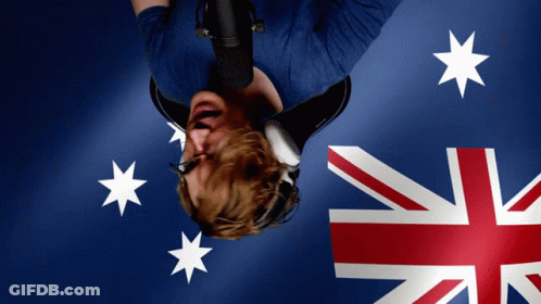 A Man Wearing Headphones Is Upside Down In Front Of A Flag GIF