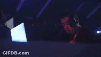 A Man Wearing Headphones Is Using A Laptop In A Dark Room GIF