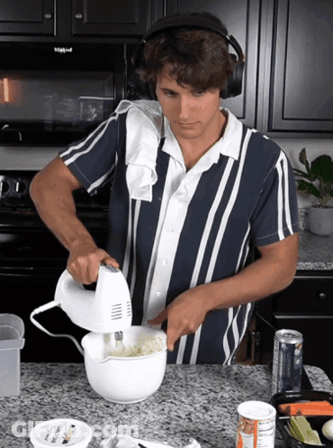 A Man Wearing Headphones Is Using A Mixer To Mix Something GIF