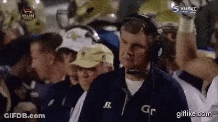 A Man Wearing Headphones Is Watching A Football Game With A Group Of People . GIF