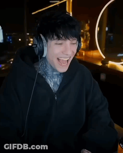 A Man Wearing Headphones Laughs In Front Of A Poster That Says Kick And Cry GIF