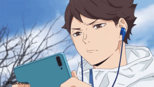 A Man Wearing Headphones Looks At His Phone GIF