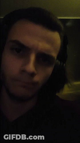 A Man Wearing Headphones Looks At The Camera In A Dark Room GIF