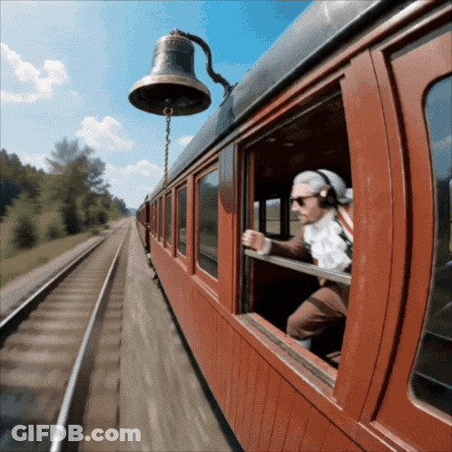 A Man Wearing Headphones Looks Out A Train Window GIF