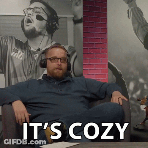 A Man Wearing Headphones Sits In A Chair With The Words " It 'S Cozy " On The Bottom GIF