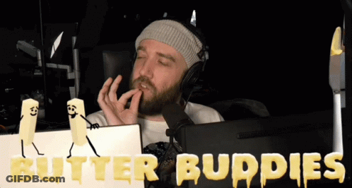 A Man Wearing Headphones Sits In Front Of A Computer Screen With Butter Buddies Written On The Screen GIF