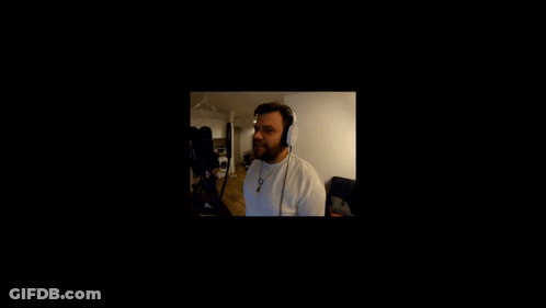 A Man Wearing Headphones Stands In Front Of A Black Screen GIF