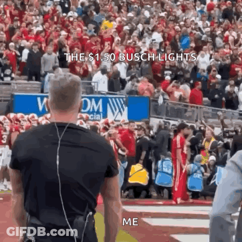 A Man Wearing Headphones Stands In Front Of A Crowd At A Football Game And Says The $ 1.50 Busch Lights Me . GIF