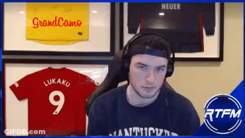 A Man Wearing Headphones Stands In Front Of A Display Of Jerseys Including One That Says Lukaku 9 GIF