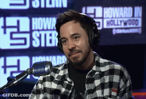 A Man Wearing Headphones Stands In Front Of A Howard J Hollywood Sign GIF