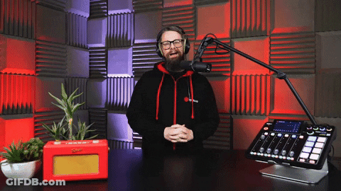 A Man Wearing Headphones Stands In Front Of A Microphone And Mixer GIF