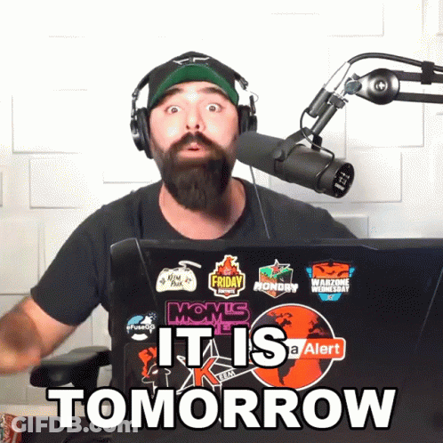 A Man Wearing Headphones Stands In Front Of A Microphone With A Laptop That Says It Is Tomorrow GIF
