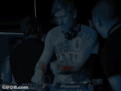A Man Wearing Headphones Stands In Front Of A Pioneer Dj Controller GIF