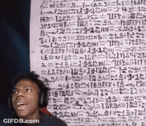 A Man Wearing Headphones Stands In Front Of A Wall With Ancient Writing GIF