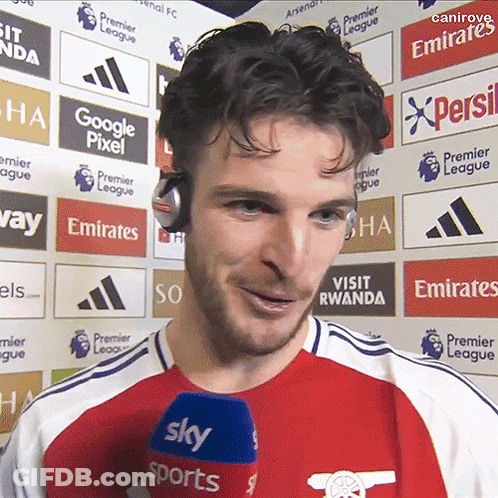 A Man Wearing Headphones Stands In Front Of A Wall With Emirates Logos On It GIF
