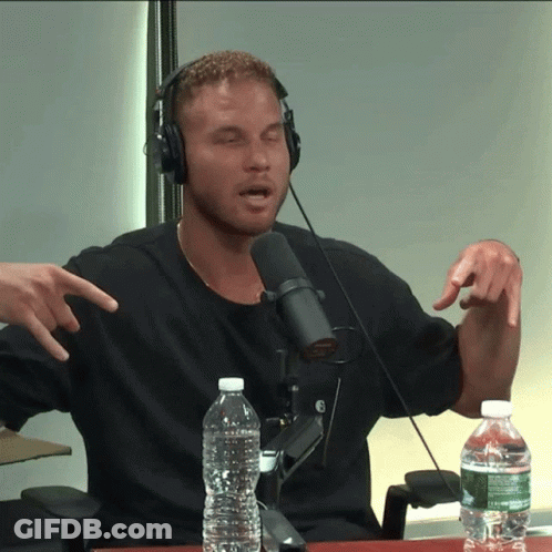 A Man Wearing Headphones Talking Into A Microphone With A Bottle Of Water In Front Of Him GIF
