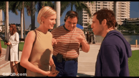 A Man Wearing Headphones Talks To Two Women GIF