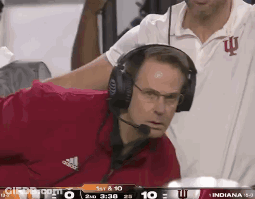 A Man Wearing Headphones Watches A Football Game Between Indiana And Iowa GIF