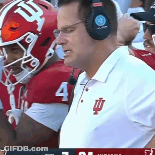A Man Wearing Headphones Watches A Football Game With A Player Wearing Number 4 GIF