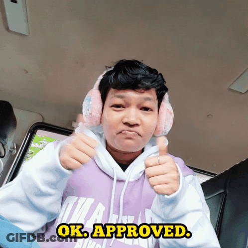 A Man Wearing Pink Ear Muffs And A Purple Hoodie Giving A Thumbs Up Sign GIF