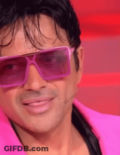 A Man Wearing Pink Sunglasses And A Pink Jacket Smiles GIF