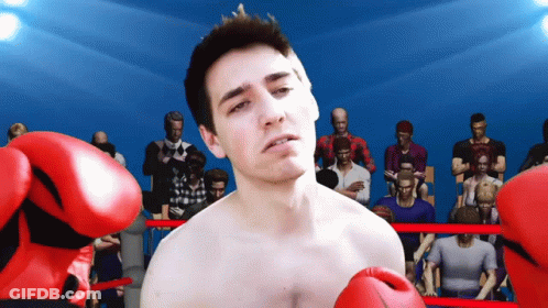 A Man Wearing Red Boxing Gloves Is Standing In A Ring GIF