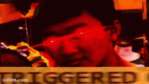 A Man Wearing Red Glasses Is Standing In Front Of A Sign That Says `` Triggered '' . GIF