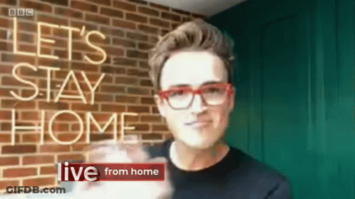 A Man Wearing Red Glasses Stands In Front Of A Brick Wall With The Words Let 'S Stay Home Live From Home GIF