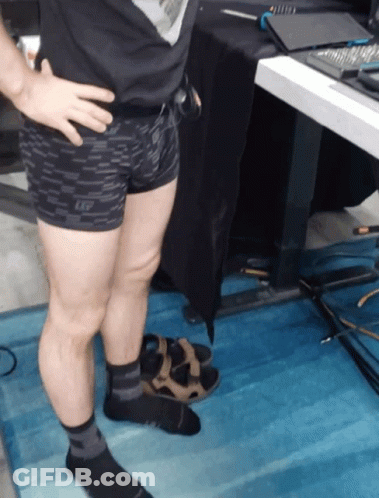 A Man Wearing Shorts And Socks Stands On A Blue Rug GIF