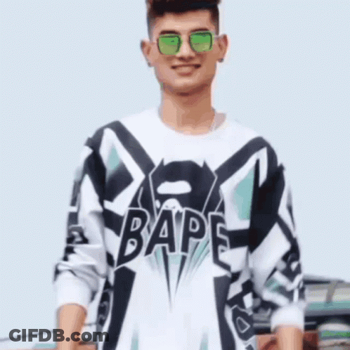A Man Wearing Sunglasses And A Bape Shirt Is Smiling . GIF