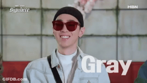 A Man Wearing Sunglasses And A Beanie Is Smiling While Sitting On A Red Couch . GIF