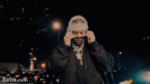 A Man Wearing Sunglasses And A Beanie Is Standing In Front Of Fireworks . GIF