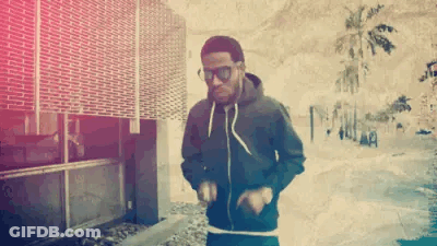A Man Wearing Sunglasses And A Black Hoodie Is Dancing On The Sidewalk . GIF