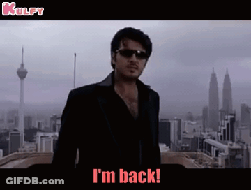 A Man Wearing Sunglasses And A Black Jacket Is Standing In Front Of A City And Says I 'M Back . GIF