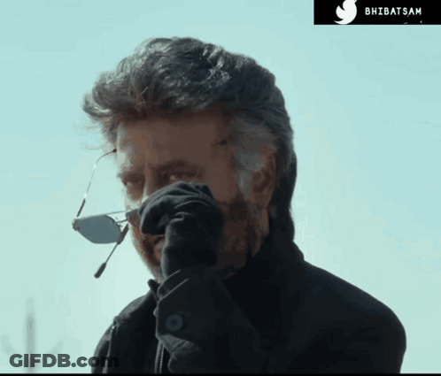 A Man Wearing Sunglasses And A Black Jacket Is Talking On A Cell Phone With A Twitter Logo In The Corner GIF