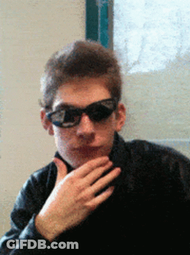 A Man Wearing Sunglasses And A Black Jacket Looks At The Camera GIF