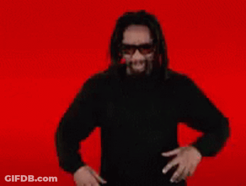 A Man Wearing Sunglasses And A Black Shirt Is Holding A White Circle In His Mouth GIF