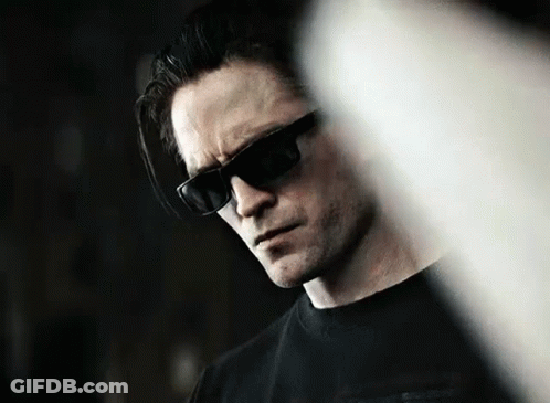 A Man Wearing Sunglasses And A Black Shirt Is Looking Down At Something . GIF