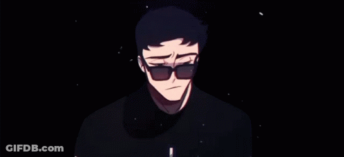 A Man Wearing Sunglasses And A Black Shirt Is Standing In A Dark Room . GIF