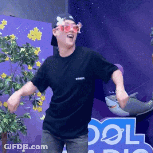 A Man Wearing Sunglasses And A Black Shirt Stands In Front Of A Sign That Says Cool GIF